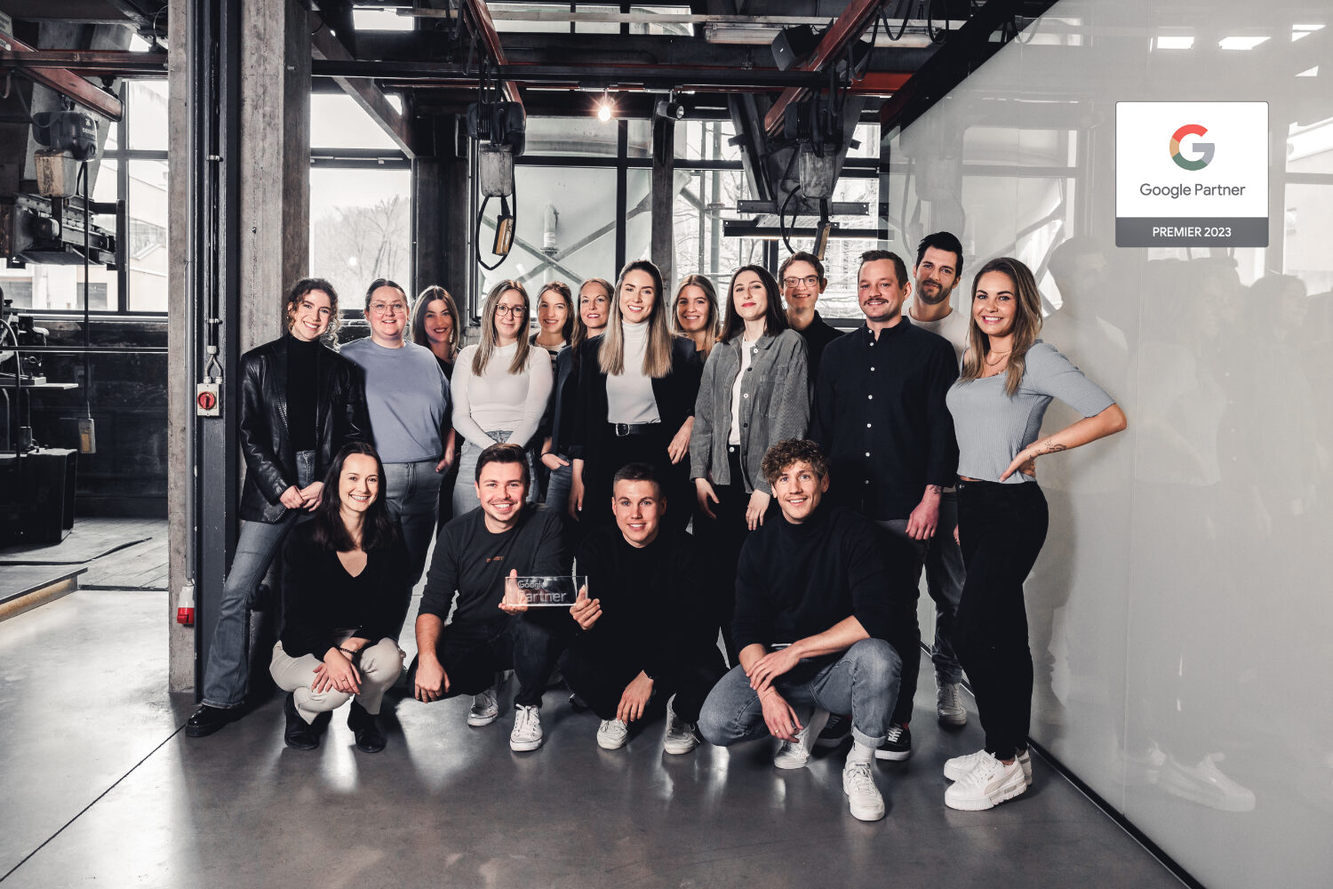 Das Kampagnen-Team von elements, bestehend aus über 15 Personen, steht zusammen und lächeln in die Kamera. Zwei Männer in der ersten Reihe halten die Google-Premium-Partner-Auszeichnung in den Händen.