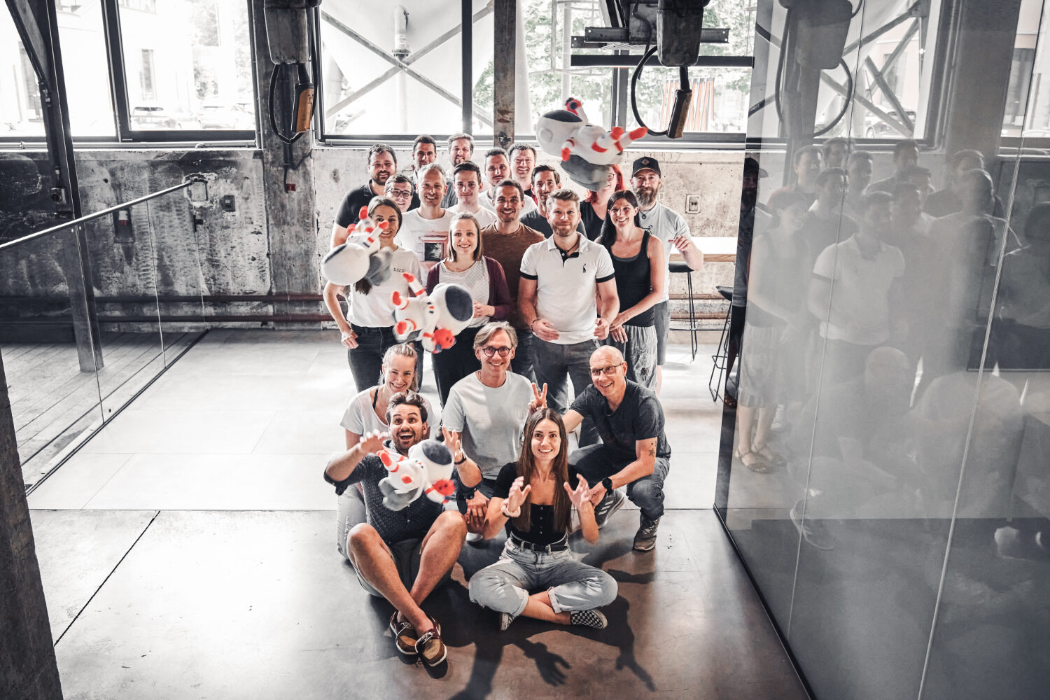 Foto von einer Gruppe Kolleg*innen, die Astronauten-Stofftiere auffangen.