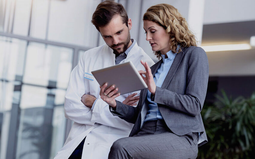 Geschäftsfrau mit Tablet im Gespräch mit Arzt