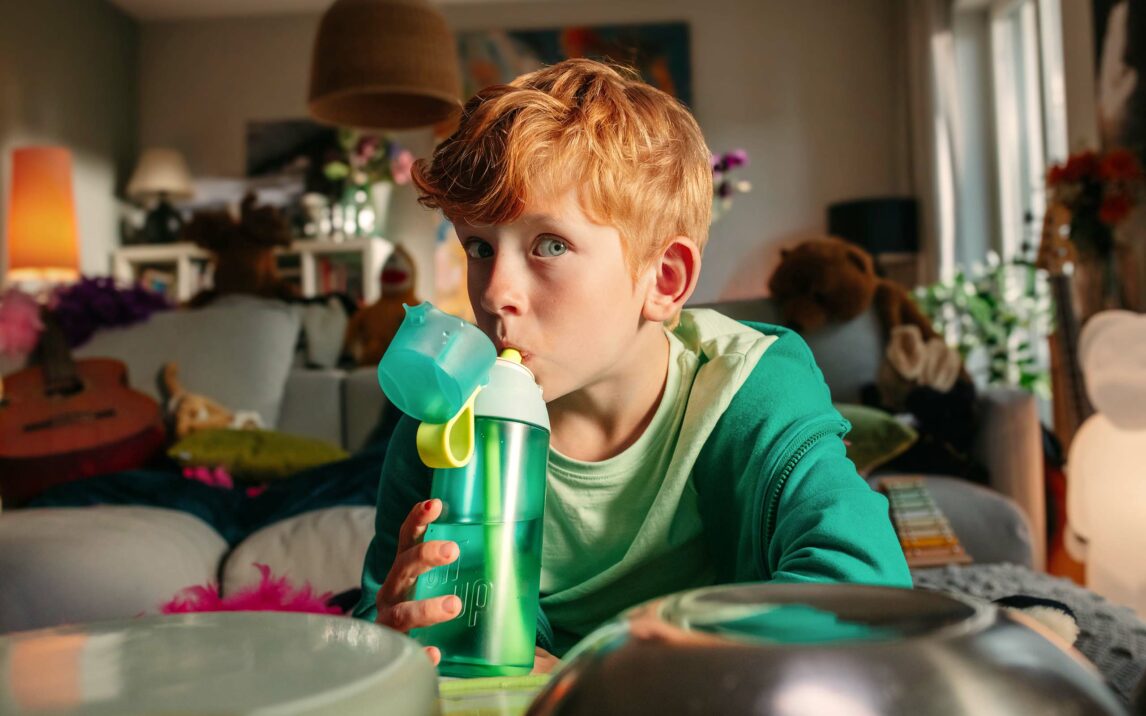 Kind, das eine Trinkflasche von air up in der Hand hält und Wasser trinkt
