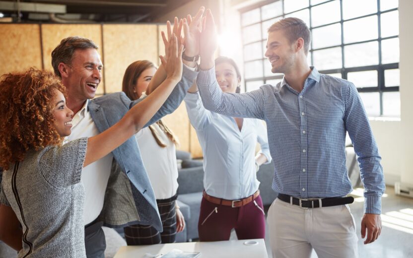 Ein Team klatscht sich gegenseitig in die Hände. Sie arbeiten zusammen und feiern einen Erfolg oder einen Meilenstein.