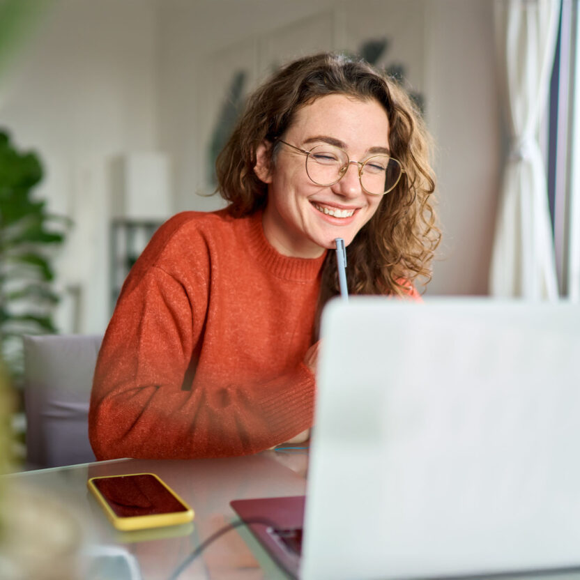 Young woman using laptop watching webinar at home
