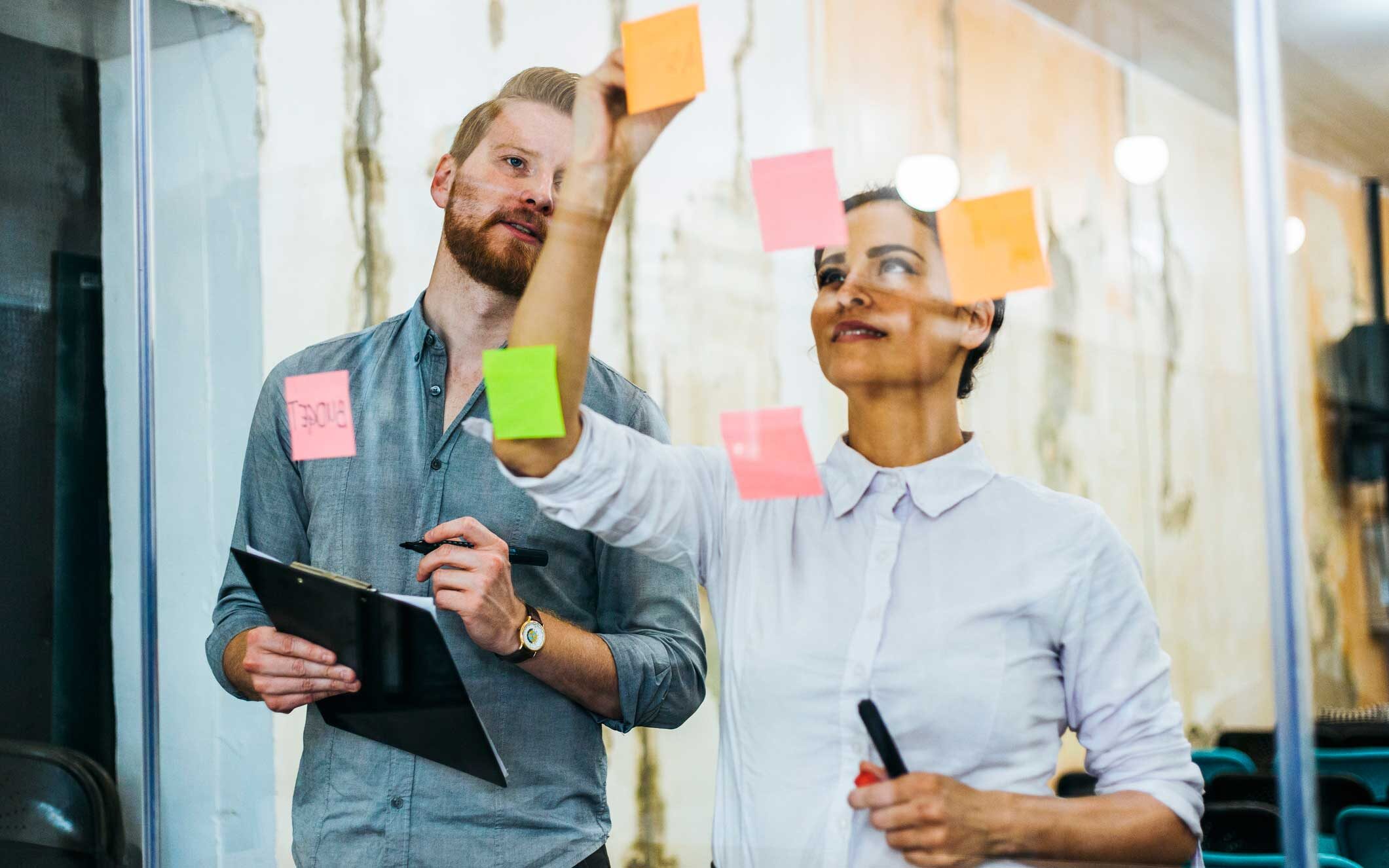 Zwei Mitarbeitende planen mit Post-its ihre KI-Strategie für den Einstieg in Agentic AI und bereiten sich auf einen AI Workshop vor.
