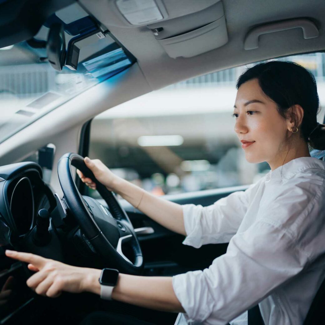 young woman sitting in car and touching screen