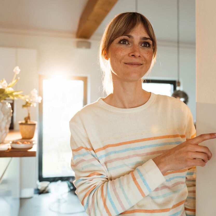contemplative woman operating thermostat on wall