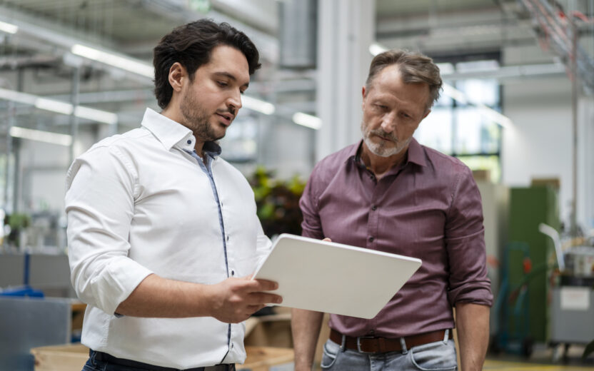 young-businessman-showing-tablet-PC-to-colleague-at-factory