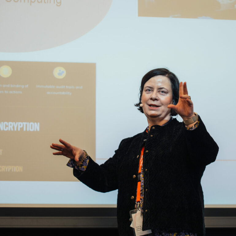 A person giving a presentation in front of a screen displaying slides about encryption and quantum computing.