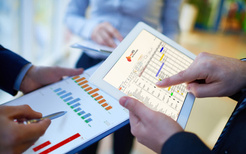 Zwei Personen überprüfen Diagramme auf einem Tablet und einem Klemmbrett und sind dabei in die Datenanalyse vertieft. Eine Person zeigt auf eine Tabelle auf dem Tablet und navigiert gekonnt durch die waySUITE-Oberfläche, um Erkenntnisse zu gewinnen.