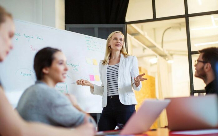 Three women and one man in front of a whiteboard in a workshop