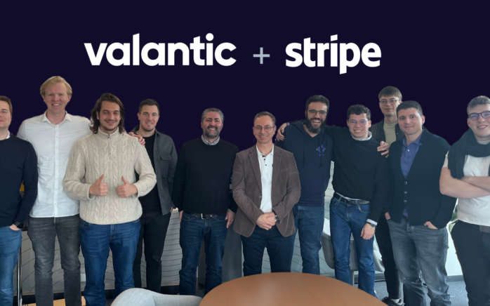 Das Experten-Team von valantic: zu sehen sind 11 Männer, die in die Kamera lächeln. Der Hintergrund ist schwarz und mit weißer Schrift steht über den Köpfen der Gruppe "valantic + stripe"