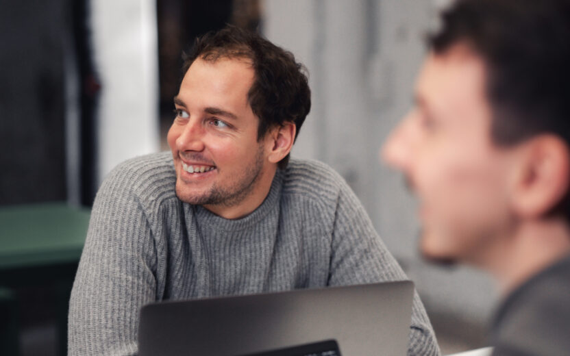 Ein Mann sitzt vor seinem Laptop und lächelt