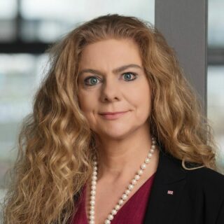 Dr. Sabina Jeschke, CEO of KI Park e.V., wearing a dark blazer, red blouse, and pearl necklace, smiling slightly in a professional portrait.