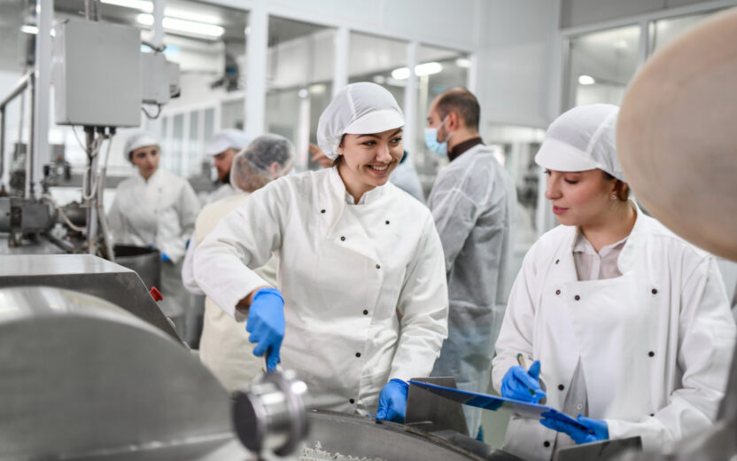 Smiling employees prepare cottage cheese mix for stuffed peppers in the factory.