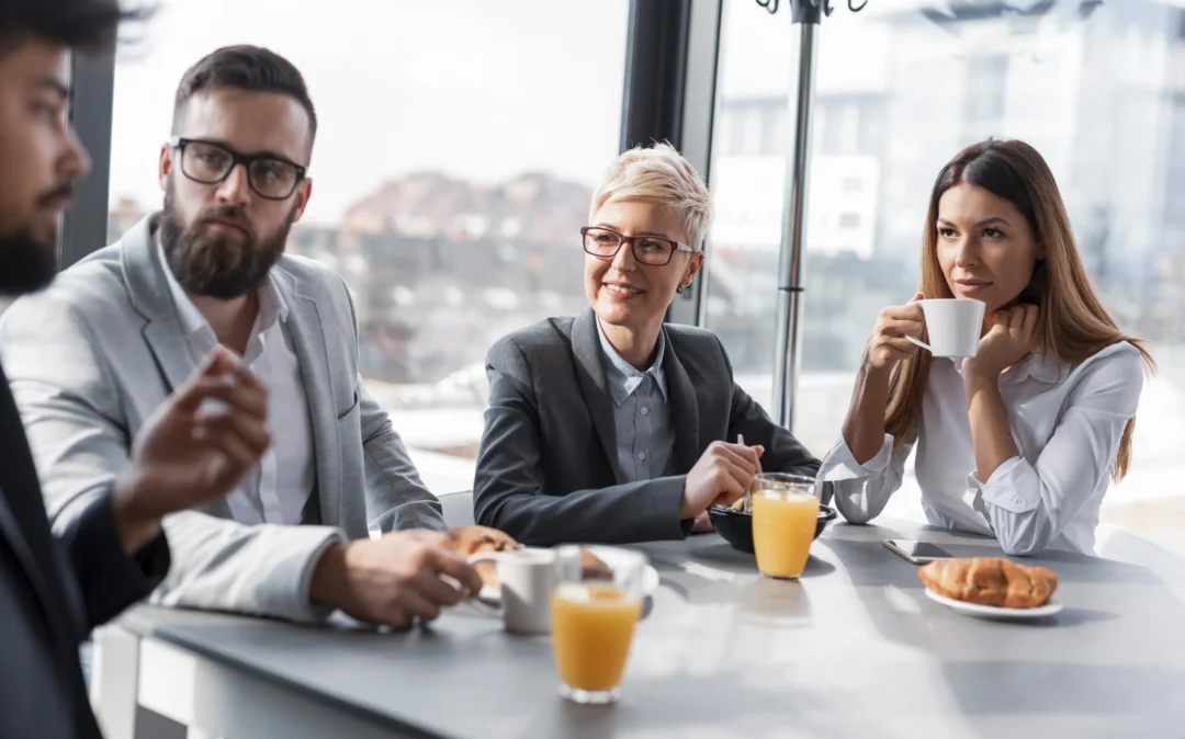 Business-Leute frühstücken im Büro mit Kaffee, O-Saft und Croissants.