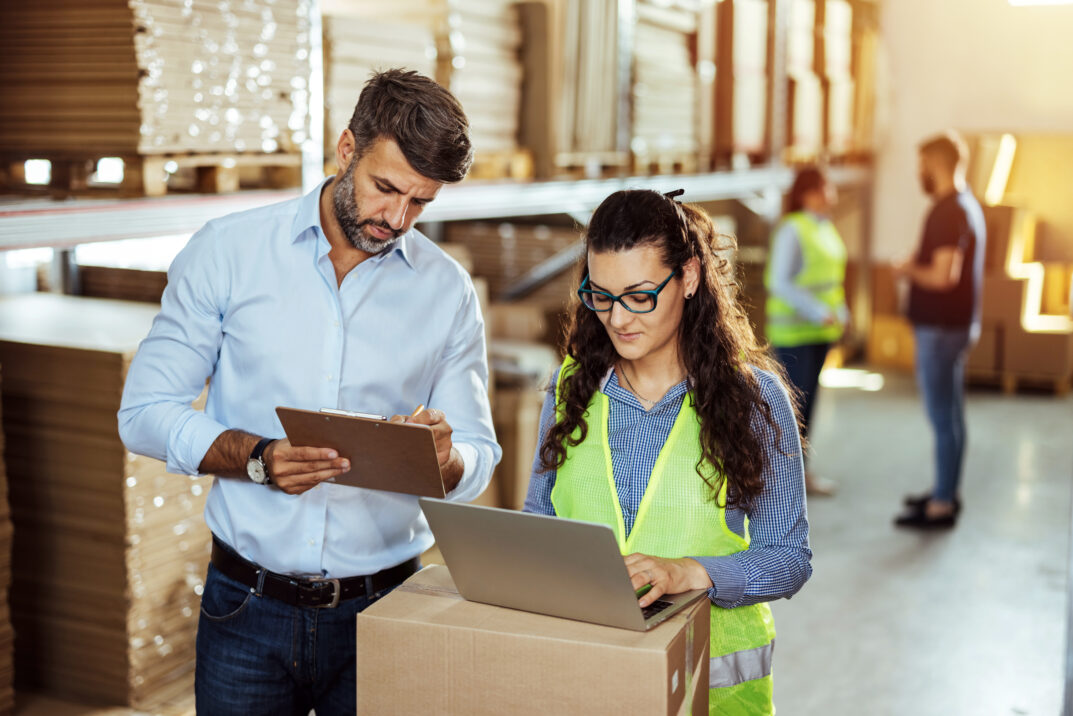 Warehouse staff looking at laptop while working.