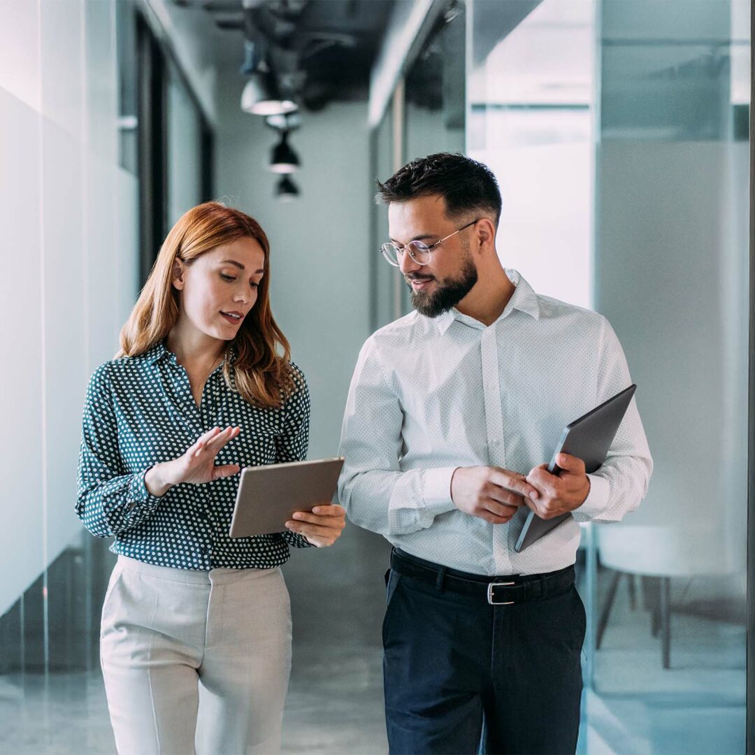 Shot of two coworkers having a discussion in modern office. Businessman and businesswoman in meeting using digital tablet and discussing business strategy. Confident business people working together in the office. Creative business persons discussing new project and sharing ideas in the workplace.