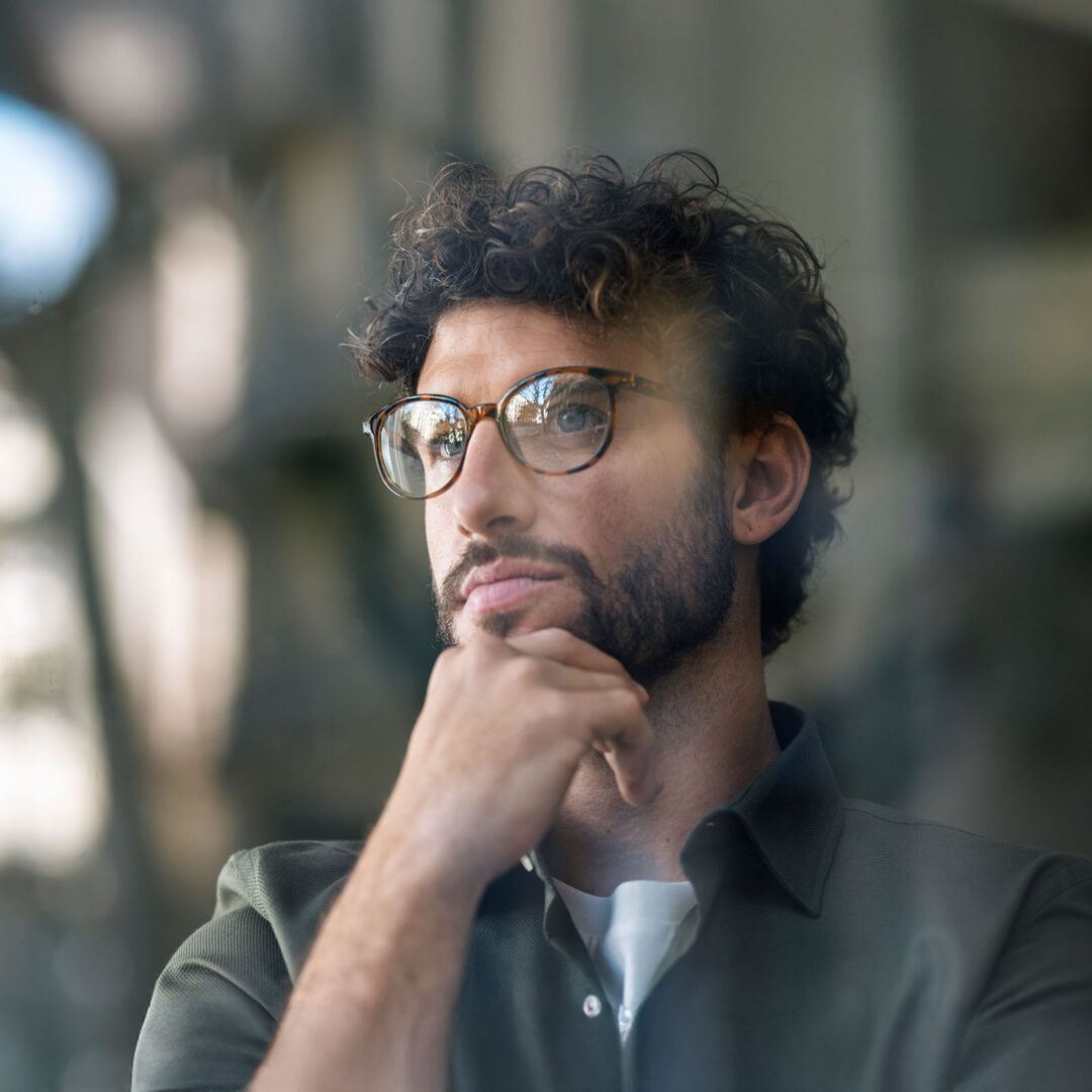 Thoughtful businessman wearing eyeglasses with hand on chin
