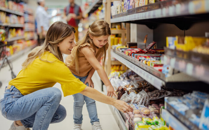 Mutter und Tochter vor dem Süßigkeitenregal im Supermarkt