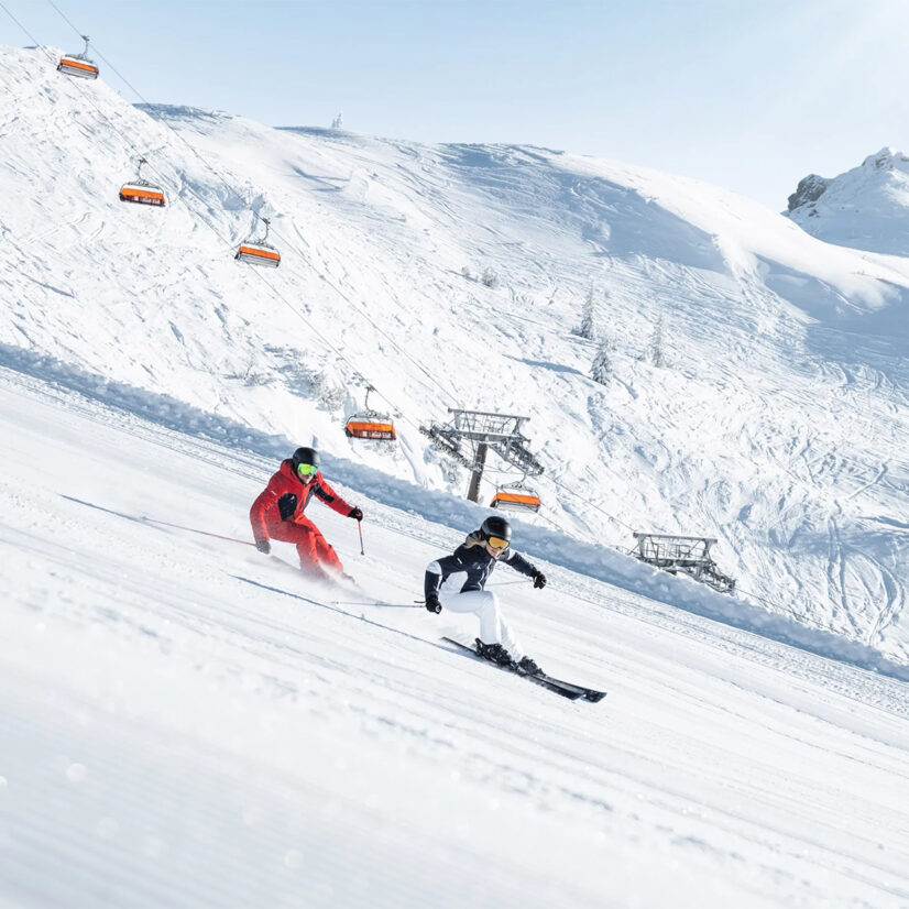 2 Skifahrer auf einer verschneiten Piste im Skigebiet von Ski amadé