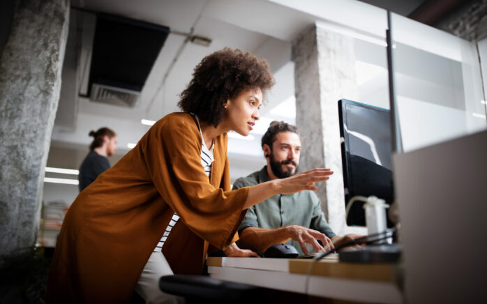 2 Personen die auf einen Bildschirm schauen und etwas besprechen