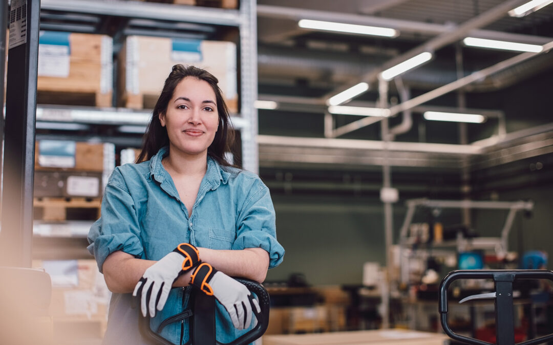Portrait of young worker leaning on pallet jack at warehouse