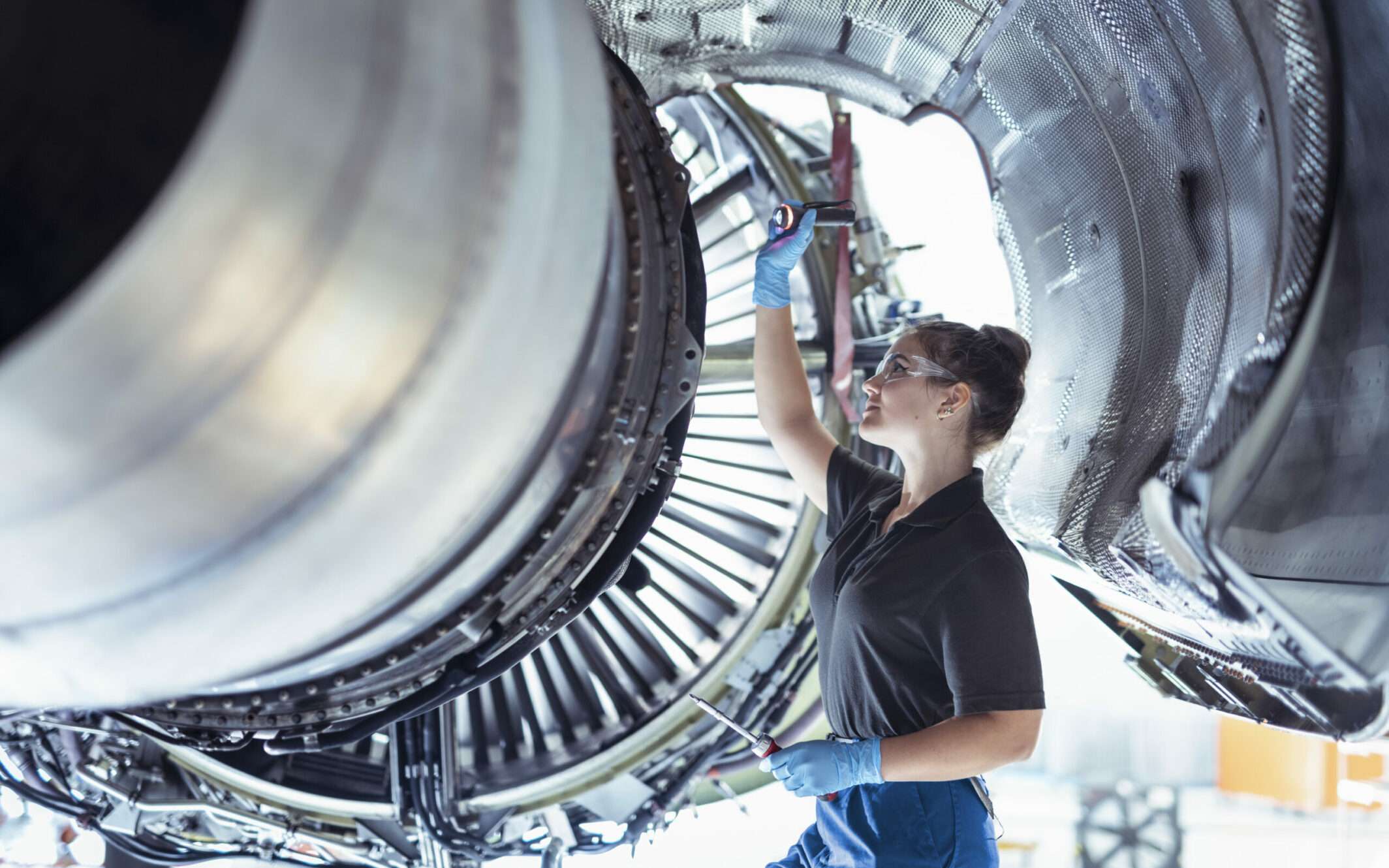 Female engineer inspecting a large aircraft turbine as part of manufacturing operations, supported by SAP Cloud ERP.