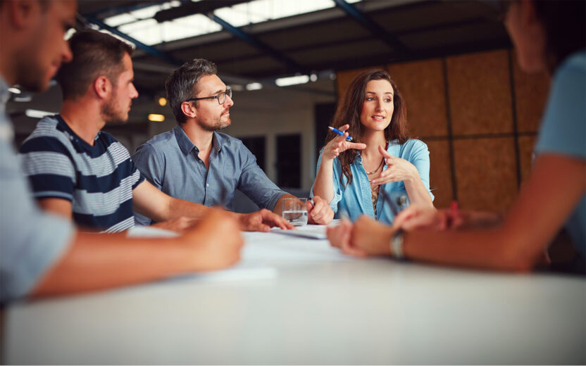 4 people are sitting at a table discussing a business matter.