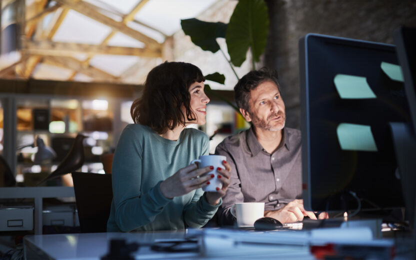 two people sitting at a desk working late in the office