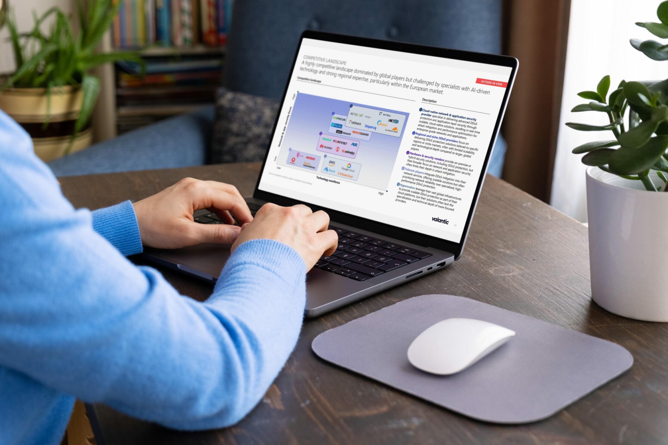 Man using laptop at home showing slide on competitive landscape in DDos Mitigation & Application Security.