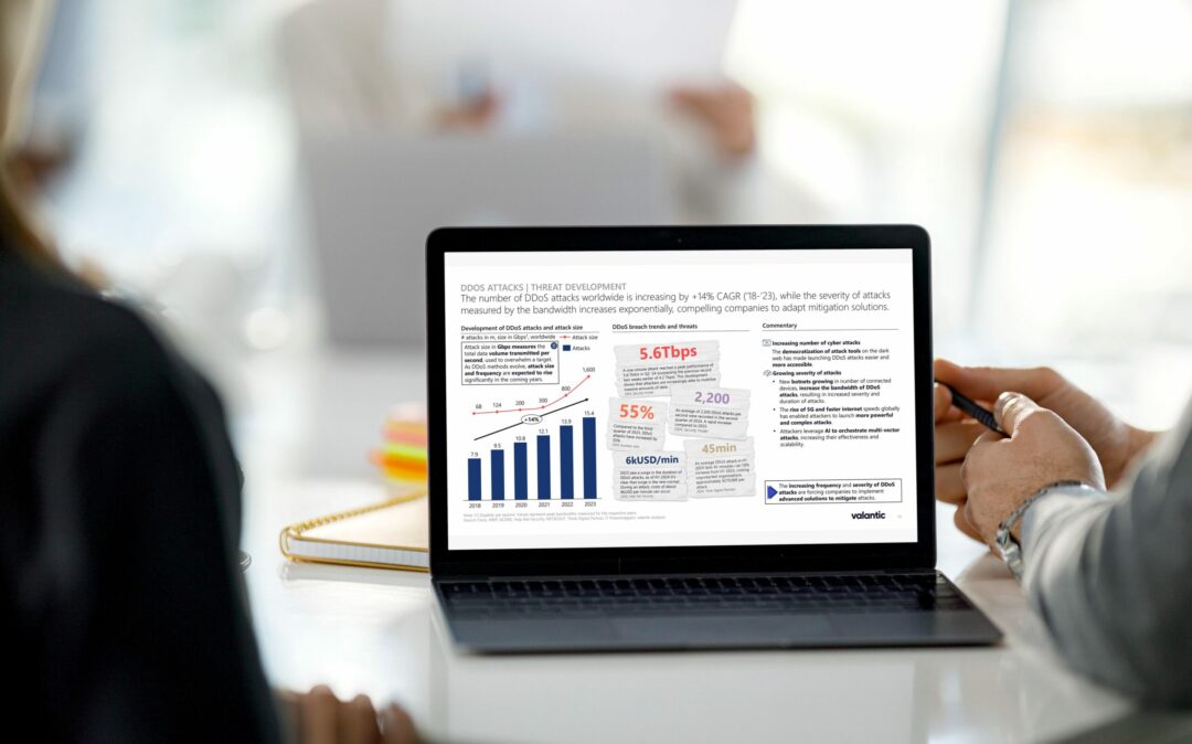 Two people with laptop table with slide on DDos mitigation market trends.