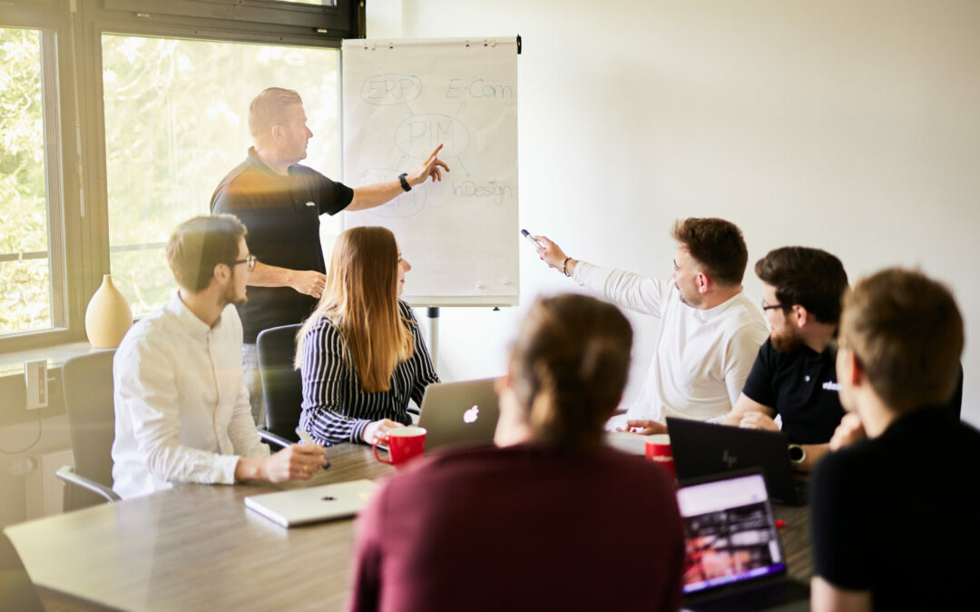 Photo from a valantic CX meeting where all participants have turned away from the camera to look at a flipchart.
