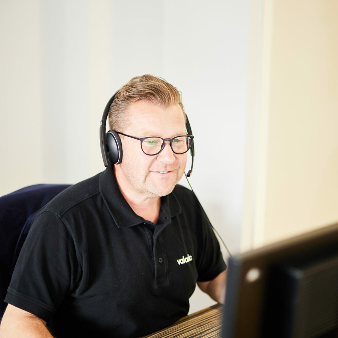 Middle-aged man sitting in front of a PC with headphones on.