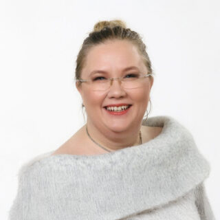 Ursula Koski, CTO for Nordics Partners, smiling in a light grey sweater with a wide collar against a white background.