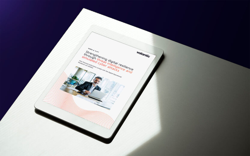 Tablet on a table displaying a valantic whitepaper titled “Strengthening digital resilience through threat intelligence and simulated cyber attacks.”