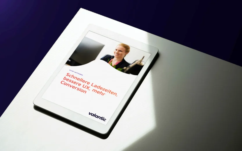 Eine Frau mit einem Lächeln sitzt an ihrem Schreibtisch und liest den Magento Hyva Leitfaden Whitepaper.