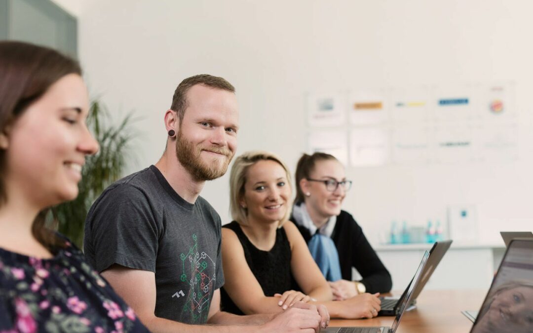 Teammitglieder führen eine Diskussion am Tisch über aktuelle Arbeitsangelegenheiten.