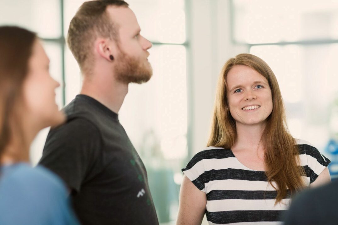 Eine Gruppe von Personen steht in einem Büro und diskutiert über Magento-Integrationsprojekte.