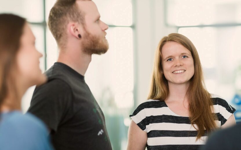 Eine Gruppe von Personen steht in einem Büro und diskutiert über Magento-Integrationsprojekte.