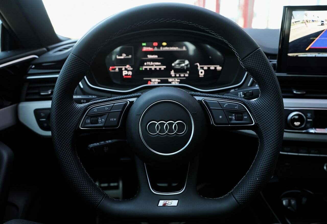 Blick auf das Lenkrad eines dunklen Audis vom Fahrersitz aus gesehen