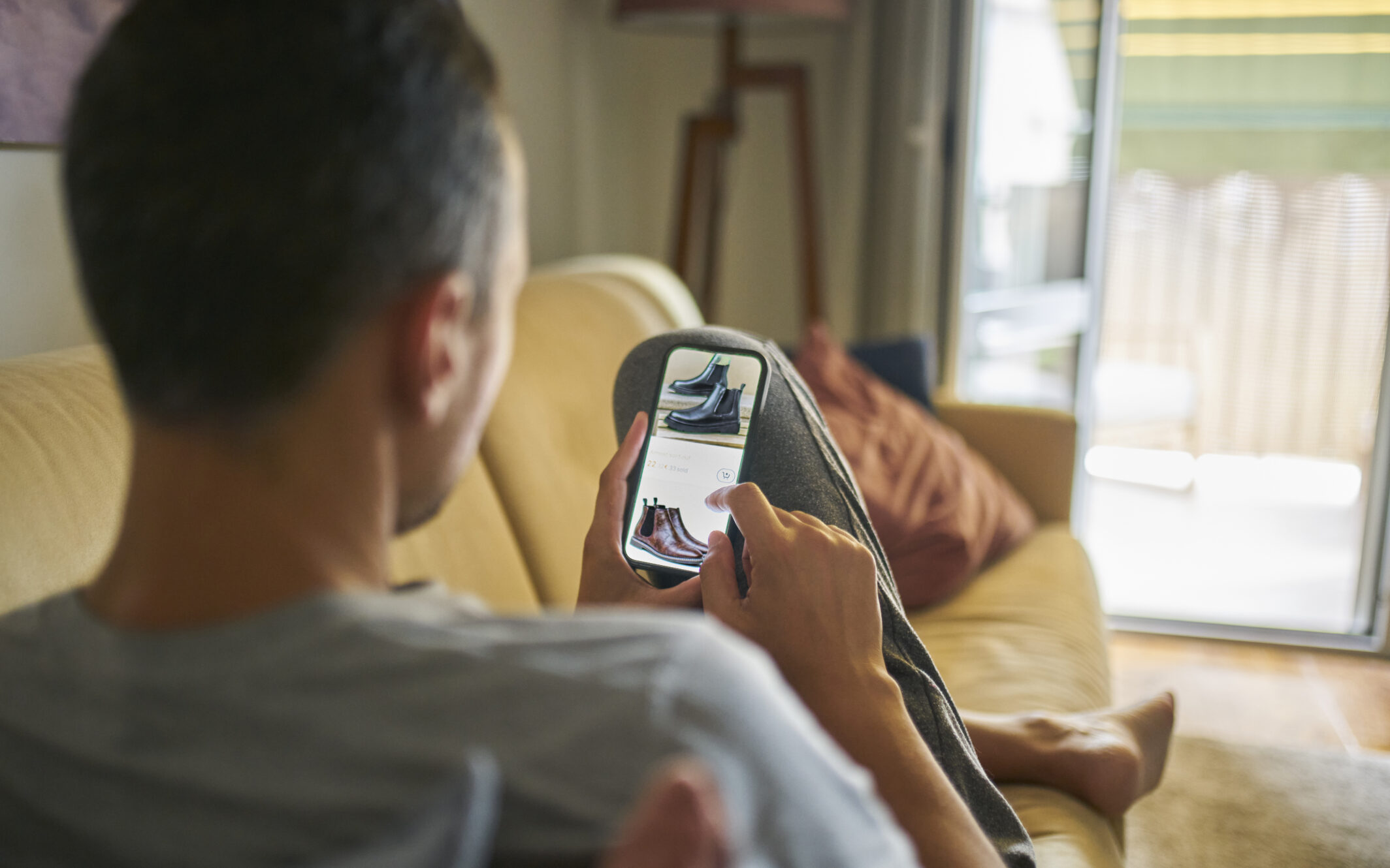 Een man die op zijn mobiele telefoon schoenen aan het kopen is