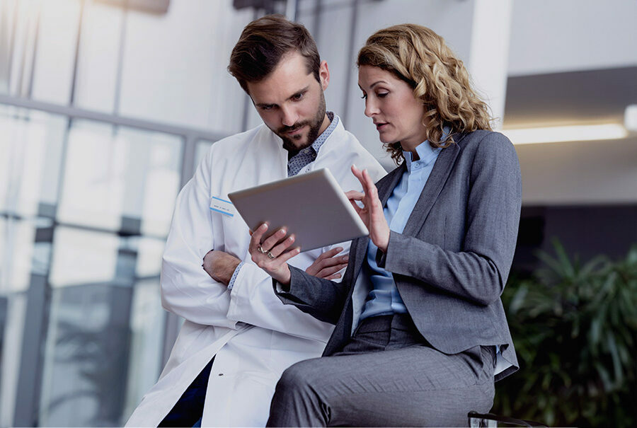 Geschäftsfrau mit Tablet im Gespräch mit Arzt