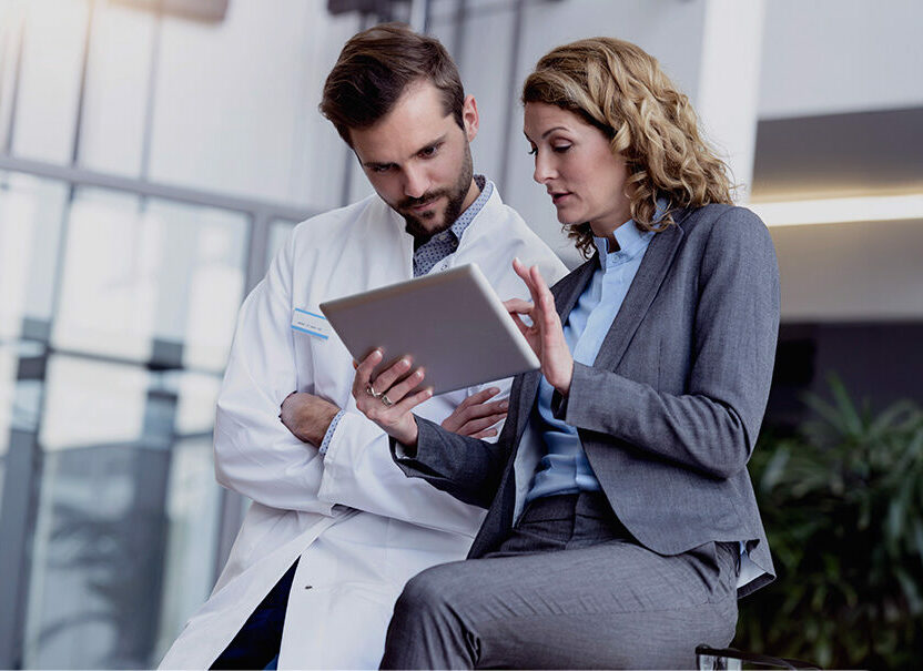 Geschäftsfrau mit Tablet im Gespräch mit Arzt