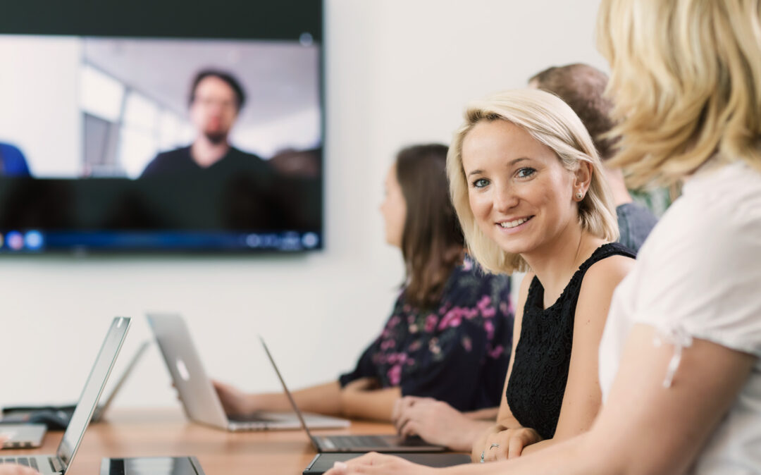 Menschen in einem Konferenzraum mit Laptops, die sich mit Adobe Commerce beschäftigen.
