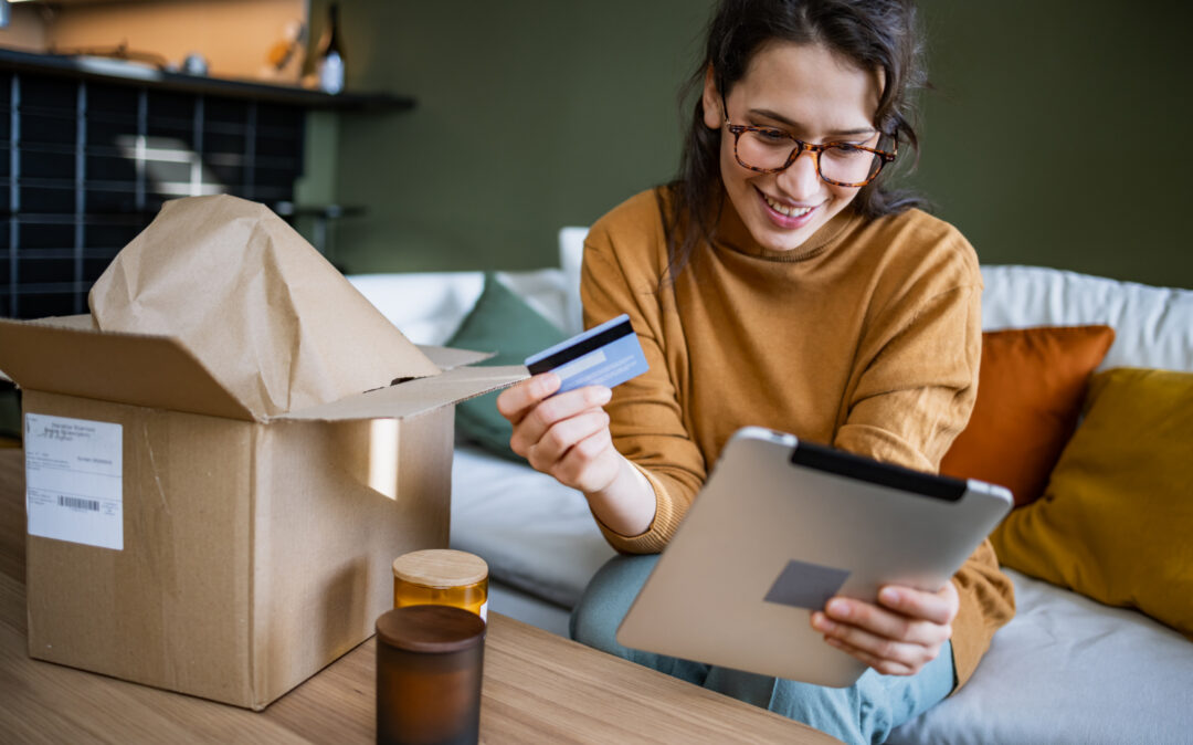 Junge Frau benutzt ein Tablet, um in einem Onlineshop zu bestellen.