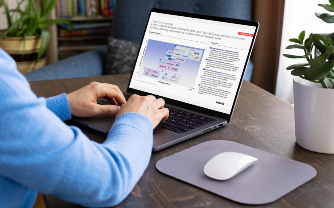 Man using laptop at home showing slide on competitive landscape in DDos Mitigation & Application Security.