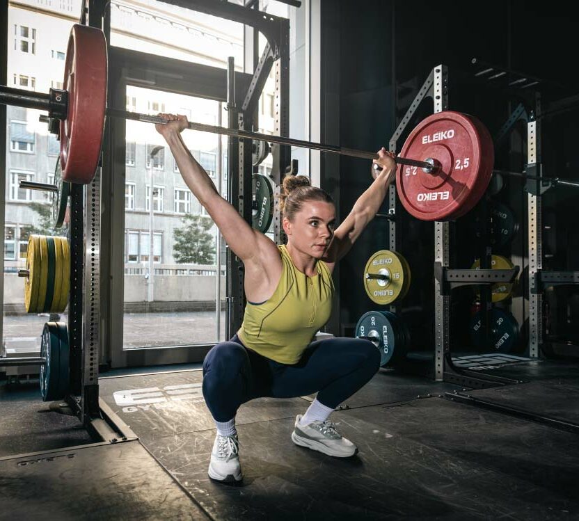 Junge Frau beim Gewichtheben im Sportstudio, toptit dank der Produkte von The Quality Group (TQG). TQG steigert die eigene Performance mit SAP Cloud ERP