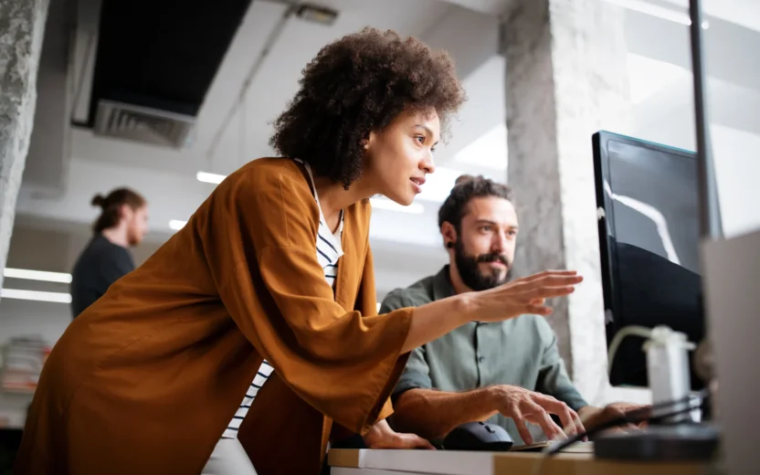 Zwei Mitarbeitende arbeiten konzentriert an einem Computer und analysieren gemeinsam Produktkonfiguratoren in einem modernen Büro.