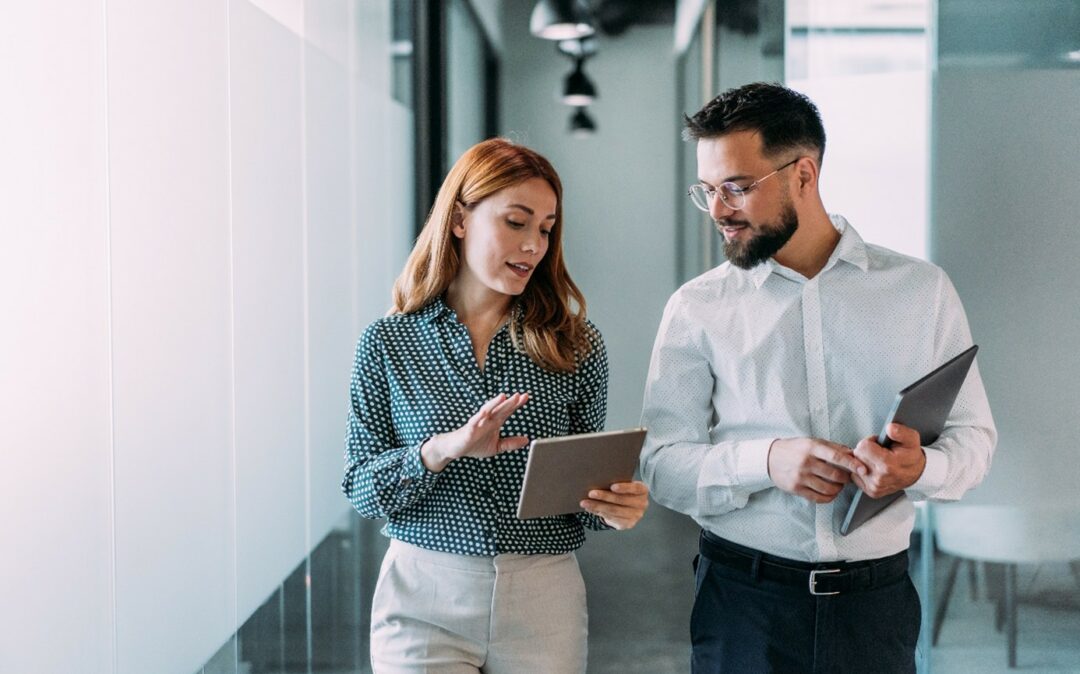 a woman and a man disussing maintenance planning with sap ibp for mro while walking down the office floor