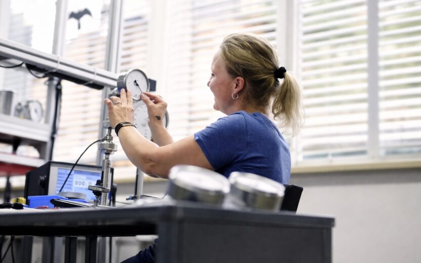 An employee of AFRISO Euro Index GmbH is working on a measuring and analysis device