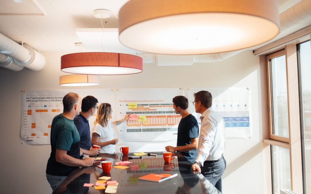 Eine Gruppe von Personen steht um einen Tisch und diskutiert Produktinformationen.